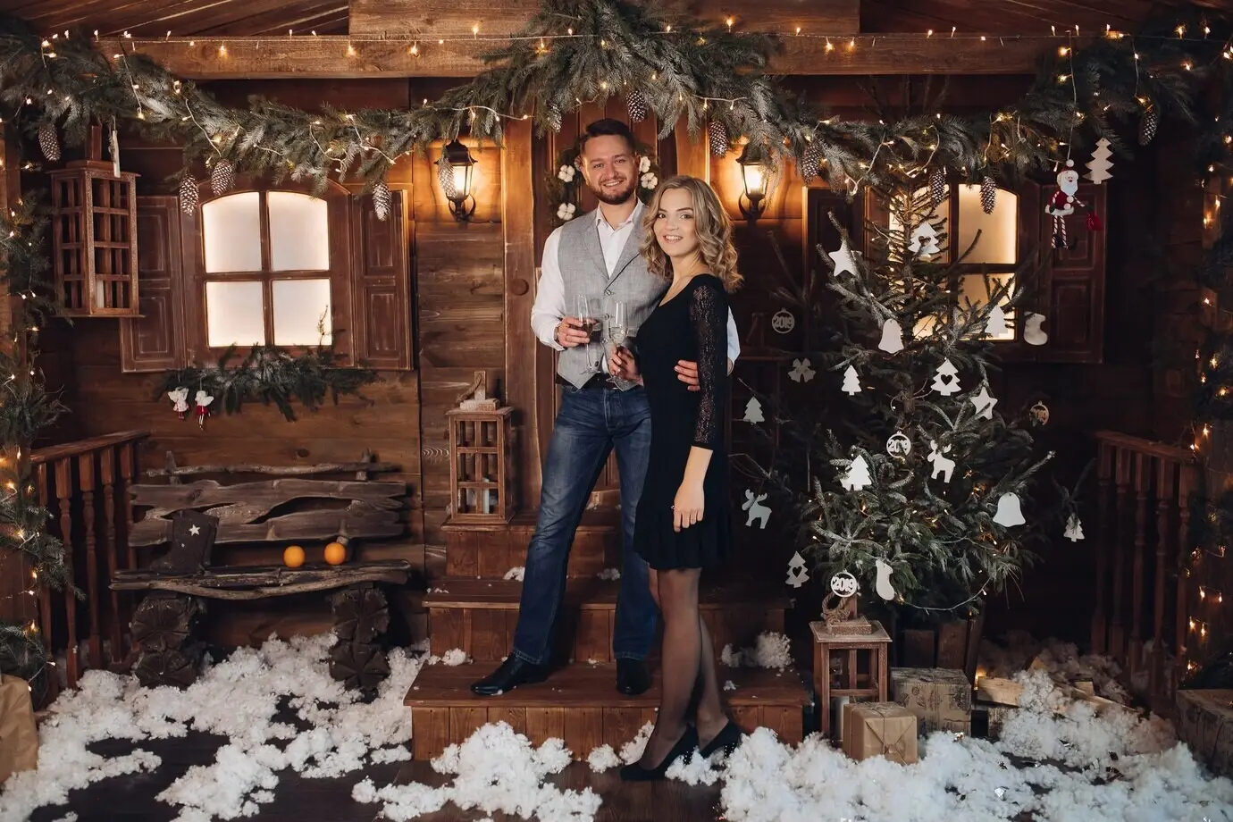 Porträt eines glücklichen jungen Paares in eleganter Kleidung, das einander lächelnd von Angesicht zu Angesicht gegenübersteht, mit zwei Gläsern Champagner.