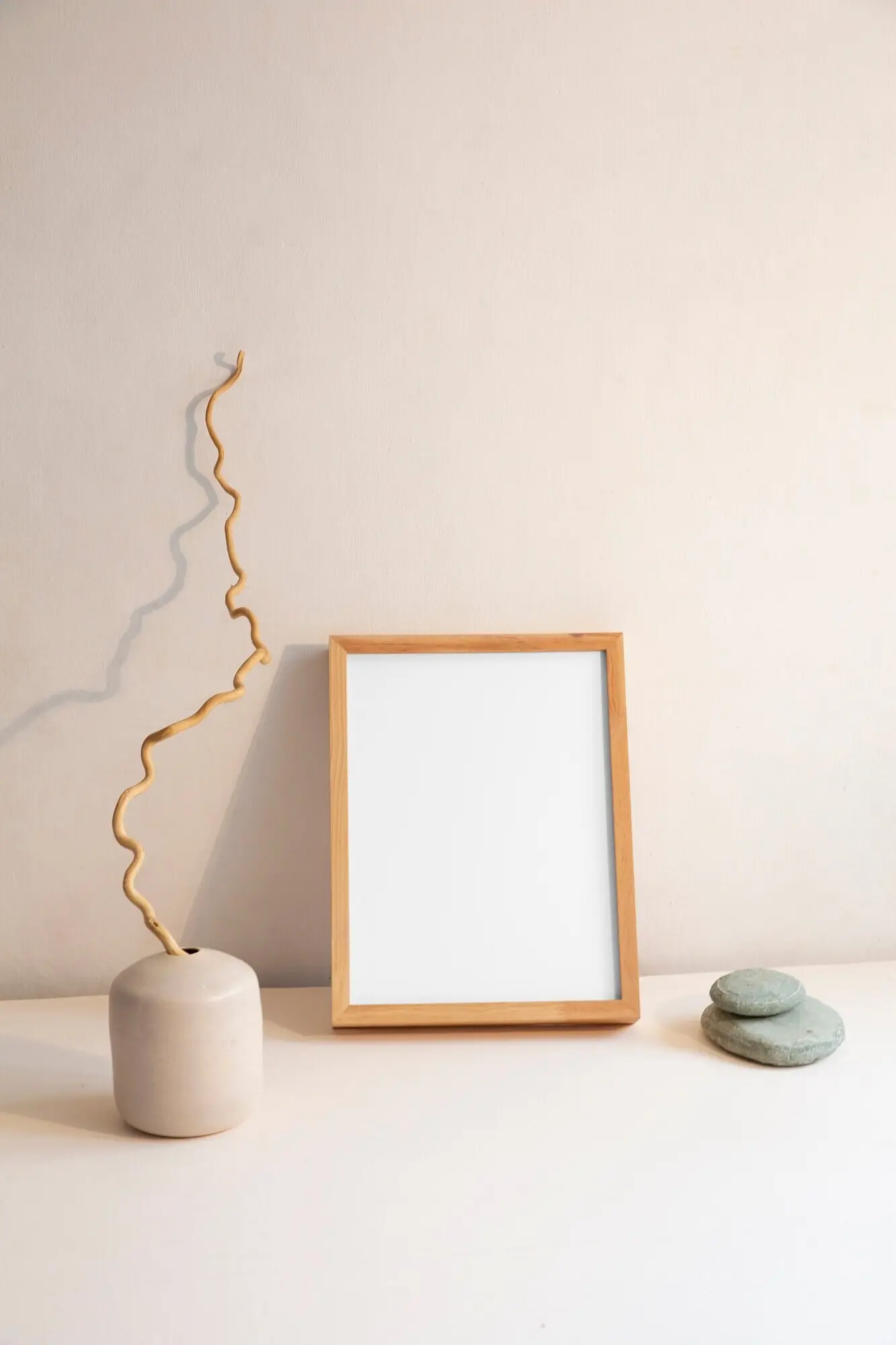 Blick auf eine Raumdekoration, die aus einem Rahmen und einer Pflanzenvase mit Steinen besteht.